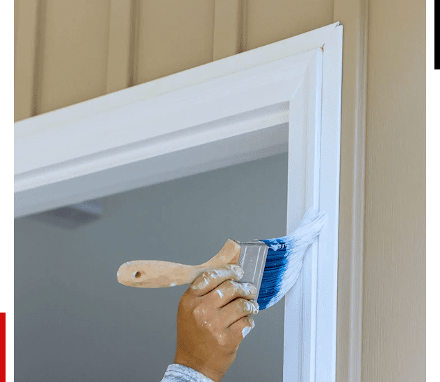 Hand painting window trim with blue paint and a brush.
