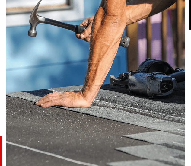 Worker hammering roofing shingles onto a roof.